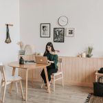 Woman working from home on a laptop in a stylish minimalist living room setting.