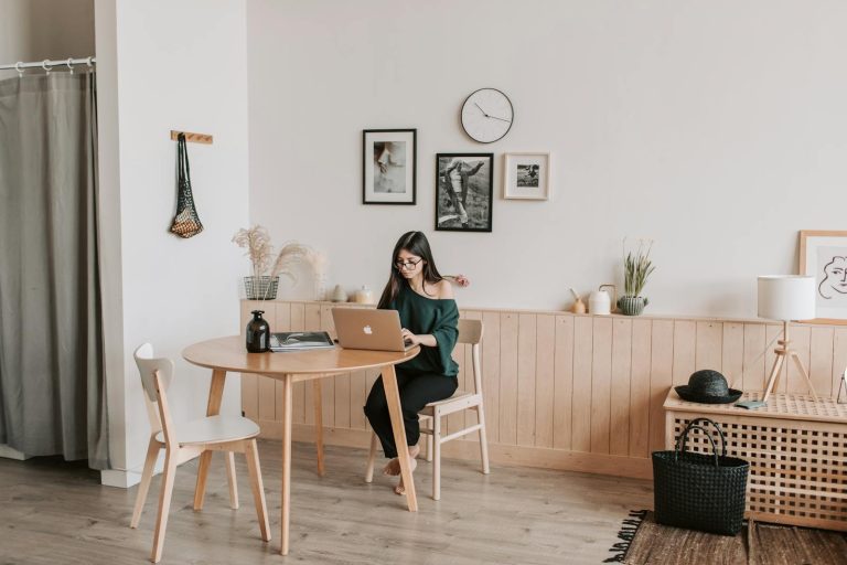 Woman working from home on a laptop in a stylish minimalist living room setting.